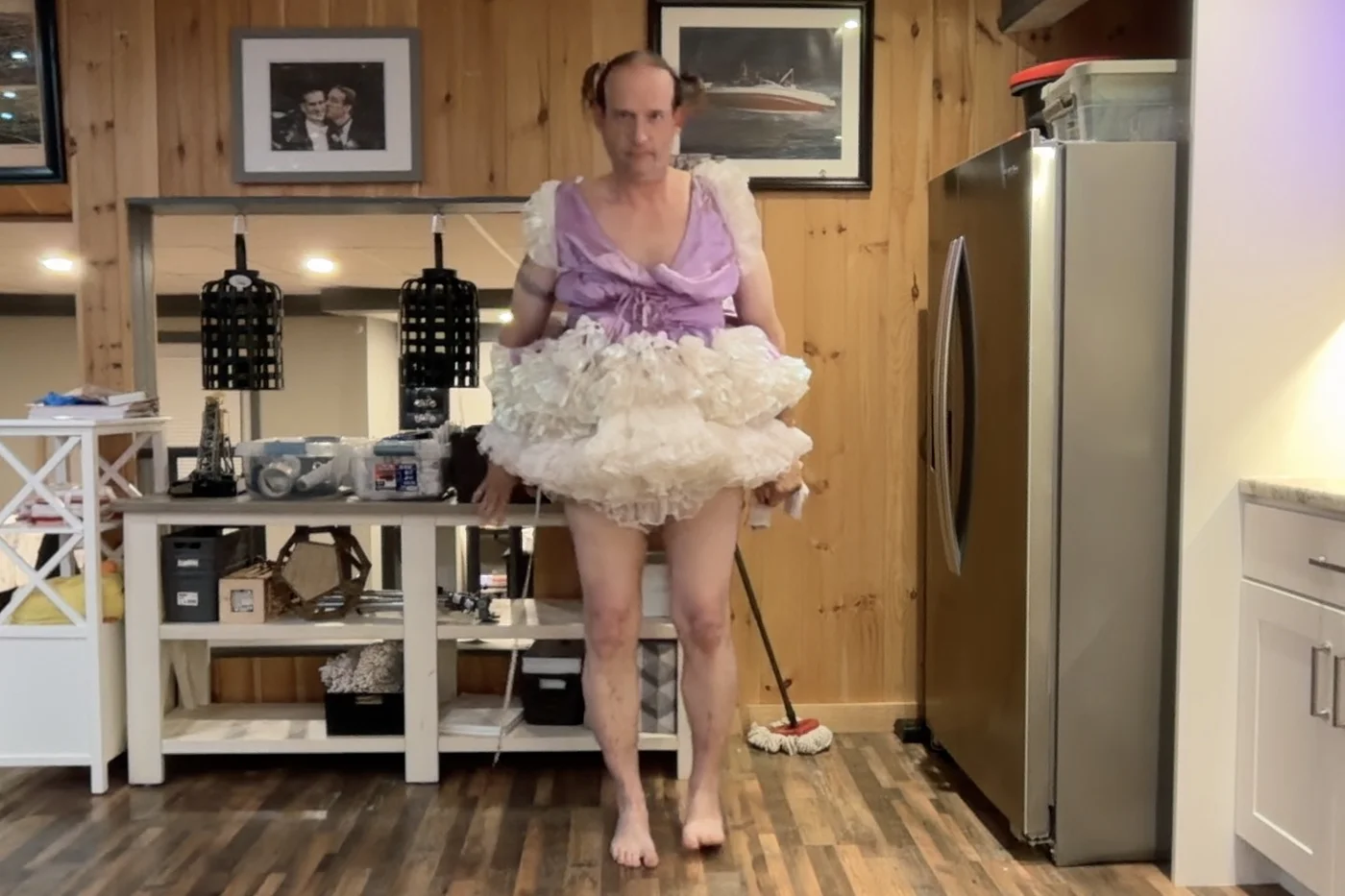 A person stands barefoot in a kitchen wearing a lavender top and a white layered ruffled skirt.